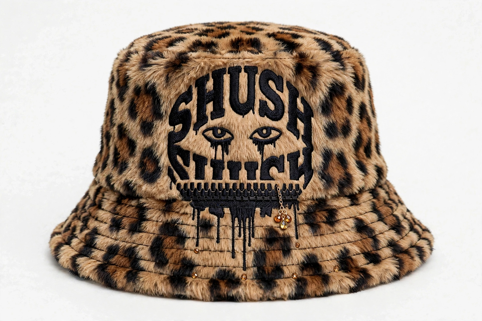 Leopard-print faux-fur SHUSH bucket hat with a clean black dripping logo face, amber gem dangle and small amber gems along the front brim