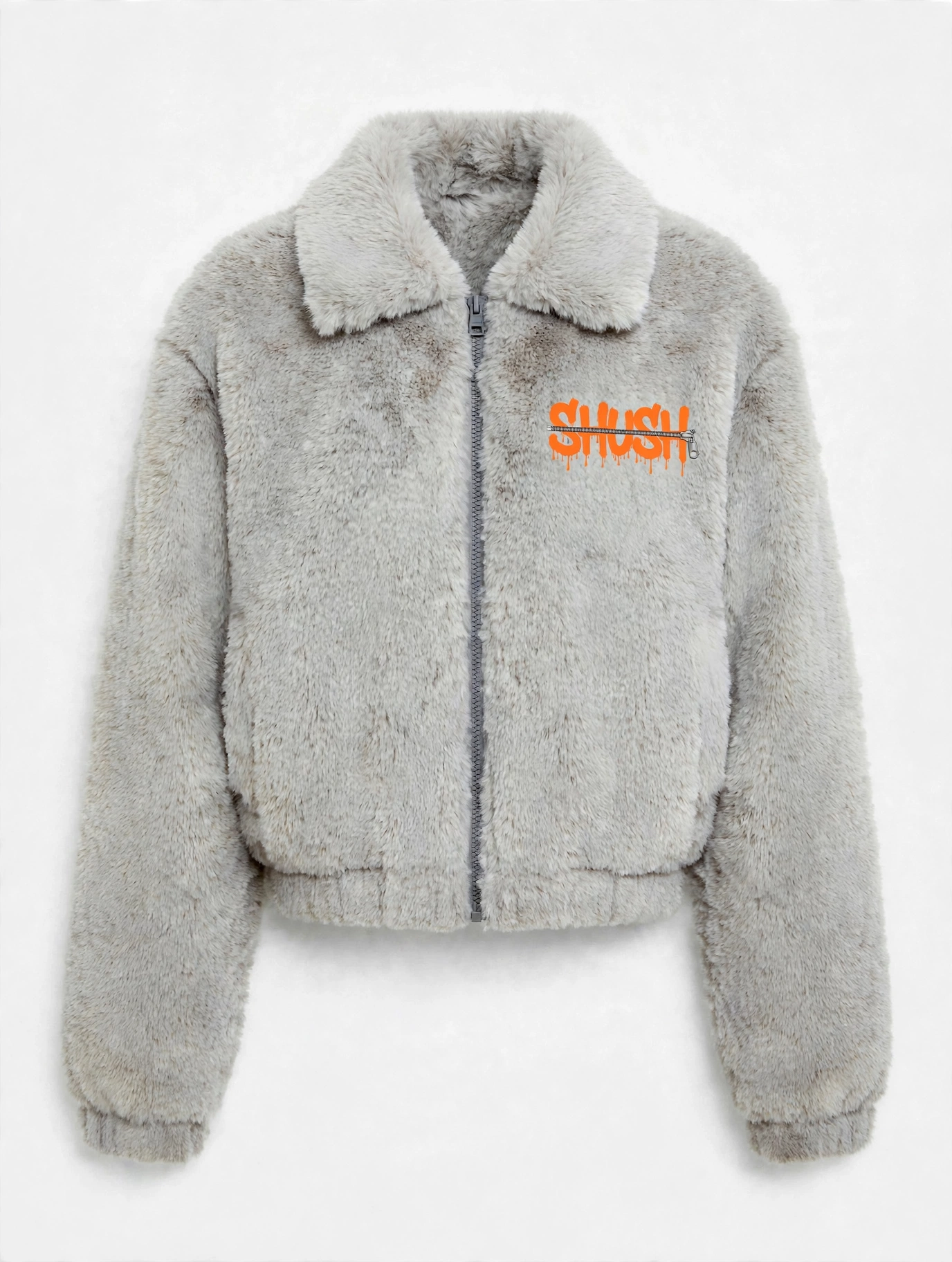 Women's cropped light gray faux-fur jacket, front view — plush fur, zip front, and a small embroidered SHUSH mark at the left shoulder: the word SHUSH in orange dripping letters zipped shut by a silver zipper