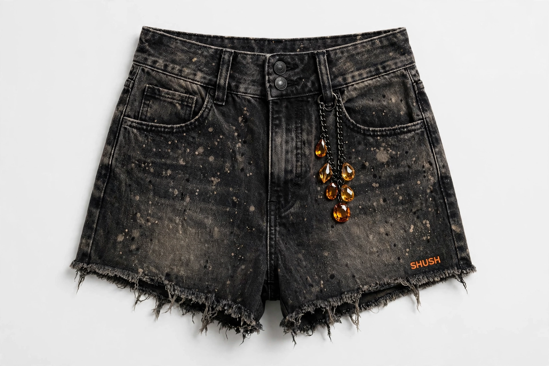 Women\u2019s black acid-wash denim cutoff shorts with bleach splatter, double-button waist, black chain with amber gem charms and orange SHUSH at the front hem